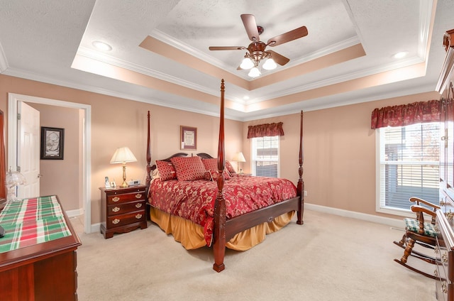 carpeted bedroom with a textured ceiling, a tray ceiling, ceiling fan, and ornamental molding