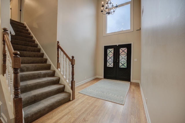 entryway with a chandelier, french doors, hardwood / wood-style floors, and a high ceiling