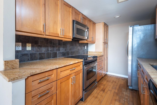 kitchen with stainless steel appliances, dark hardwood / wood-style flooring, decorative backsplash, and light stone countertops