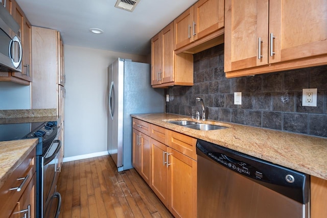 kitchen featuring stainless steel appliances, light stone counters, dark hardwood / wood-style floors, sink, and backsplash