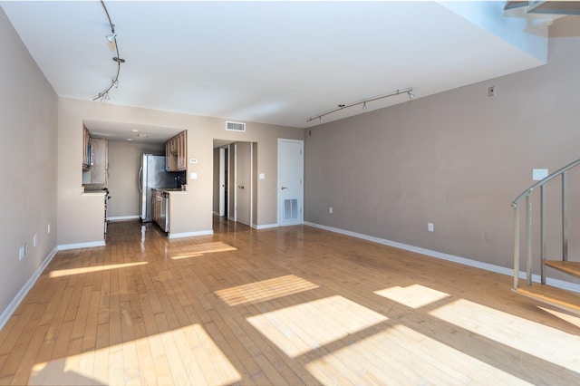 unfurnished living room featuring light wood-type flooring and rail lighting