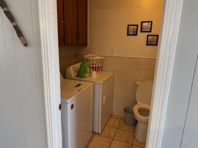 bathroom with washing machine and dryer, tile patterned flooring, tile walls, and toilet