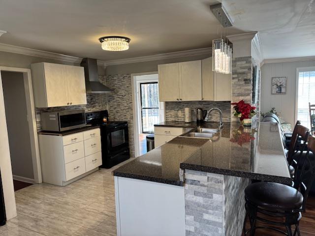 kitchen featuring pendant lighting, wall chimney range hood, sink, black / electric stove, and kitchen peninsula