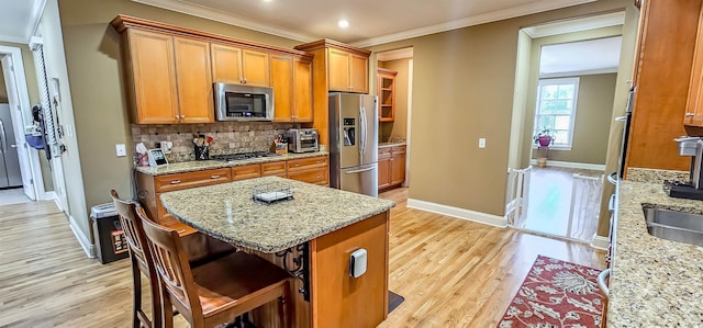 kitchen featuring a breakfast bar, backsplash, light hardwood / wood-style flooring, light stone counters, and stainless steel appliances