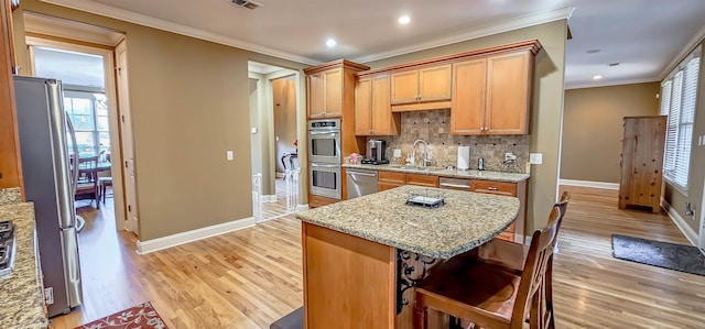 kitchen with light stone countertops, sink, backsplash, light hardwood / wood-style floors, and appliances with stainless steel finishes