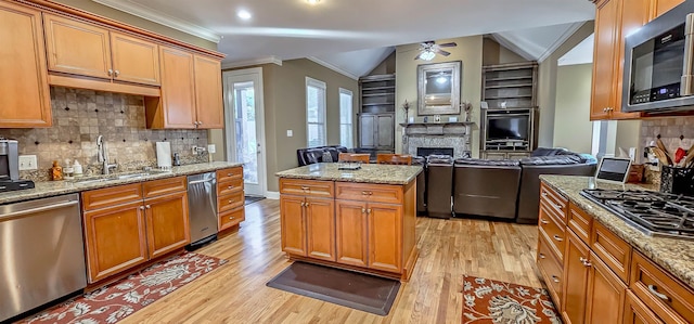 kitchen featuring ceiling fan, sink, crown molding, vaulted ceiling, and appliances with stainless steel finishes