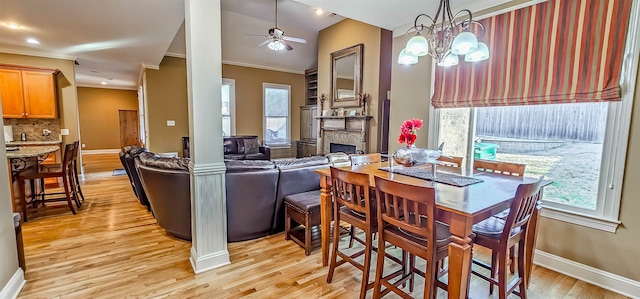 dining room featuring ornate columns, light hardwood / wood-style flooring, ceiling fan with notable chandelier, and ornamental molding