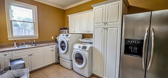 washroom with cabinets, crown molding, sink, light tile patterned floors, and washing machine and clothes dryer