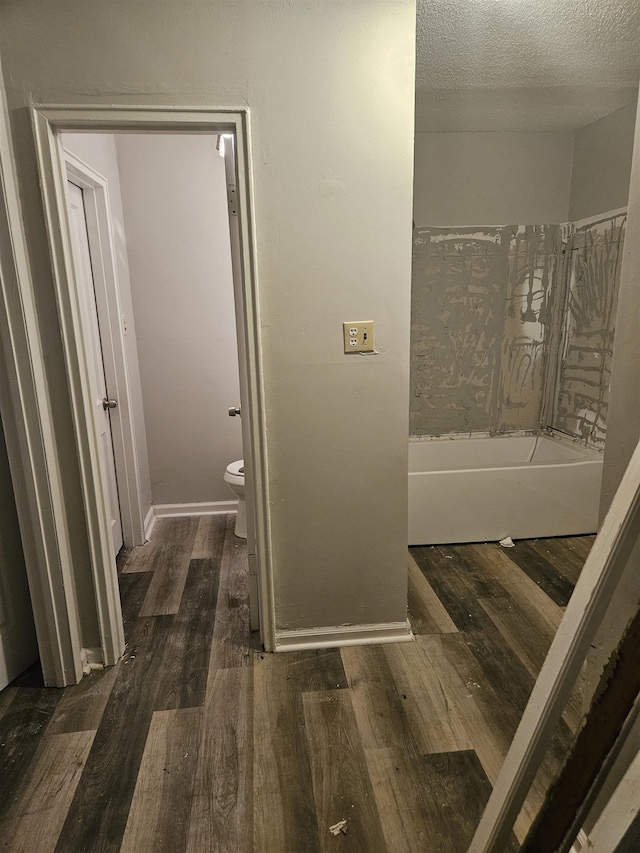 bathroom with a textured ceiling, hardwood / wood-style flooring, and toilet