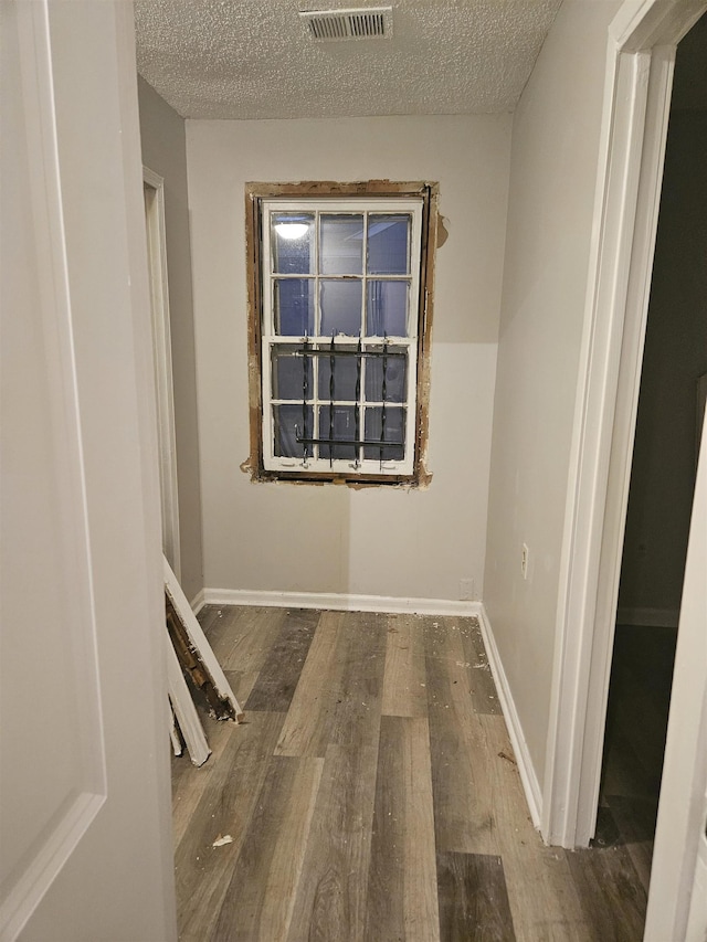 empty room with hardwood / wood-style floors and a textured ceiling