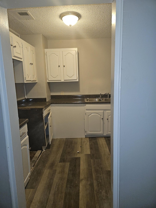 kitchen with dark hardwood / wood-style flooring, white cabinets, a textured ceiling, and sink