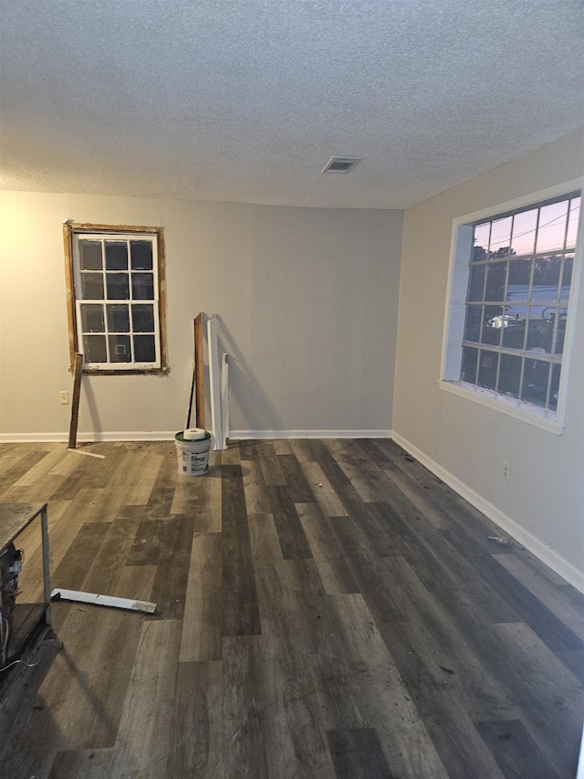 spare room featuring a textured ceiling and dark wood-type flooring