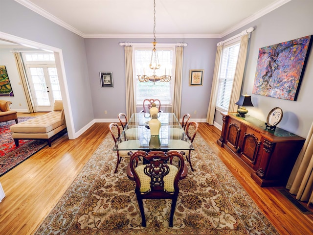 dining space with light hardwood / wood-style flooring, french doors, crown molding, and a chandelier