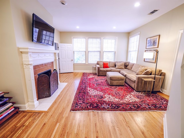 living room featuring a tiled fireplace and light hardwood / wood-style flooring