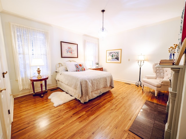 bedroom with an inviting chandelier, ornamental molding, and hardwood / wood-style flooring