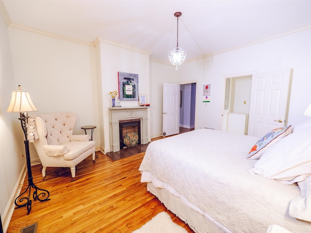 bedroom with wood-type flooring, crown molding, and a chandelier