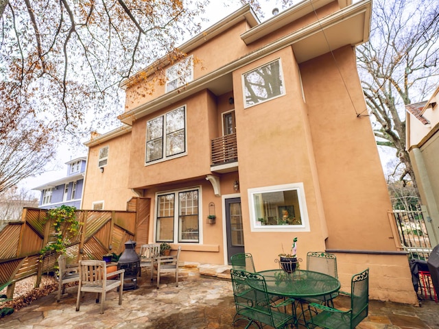 rear view of property featuring a patio and a balcony