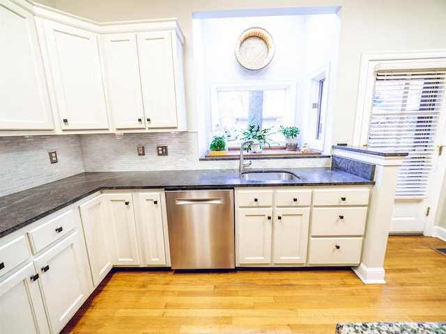 kitchen with white cabinets, light hardwood / wood-style floors, stainless steel dishwasher, and sink