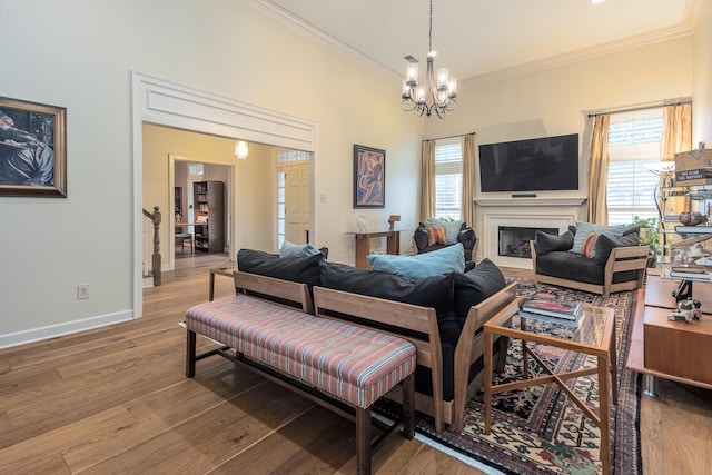 living room with light hardwood / wood-style flooring, a notable chandelier, a wealth of natural light, and ornamental molding