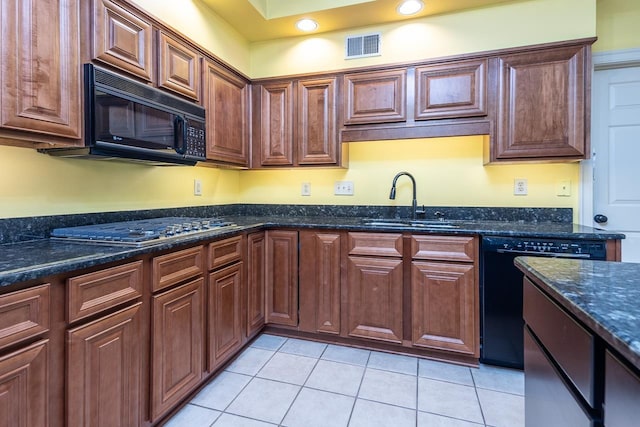 kitchen with light tile patterned floors, dark stone counters, sink, and black appliances