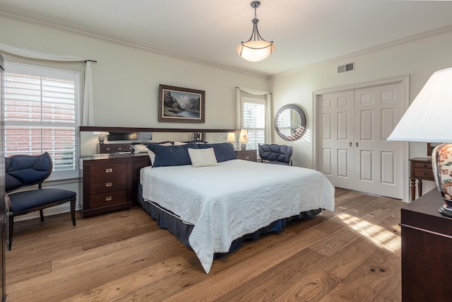 bedroom with crown molding, light hardwood / wood-style flooring, and a closet