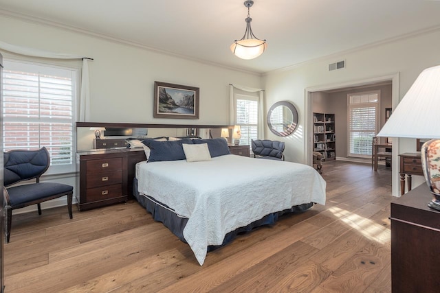 bedroom with crown molding and light wood-type flooring