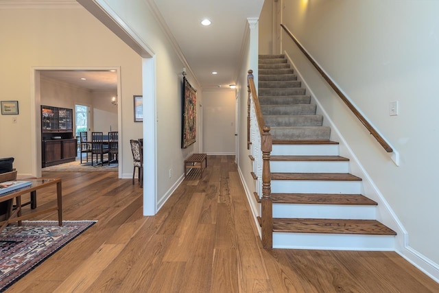 stairs with crown molding and hardwood / wood-style flooring