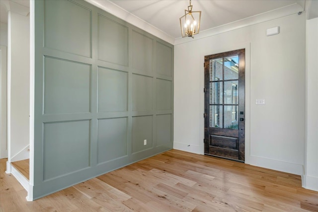 entrance foyer featuring crown molding, a chandelier, and light hardwood / wood-style floors