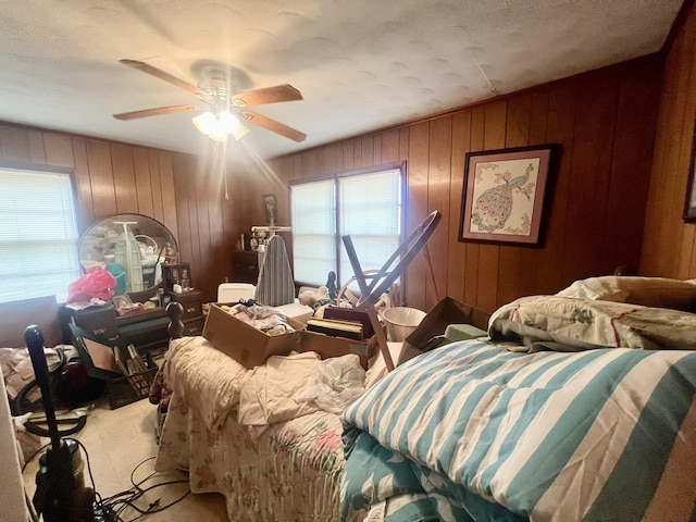 bedroom featuring ceiling fan and wood walls