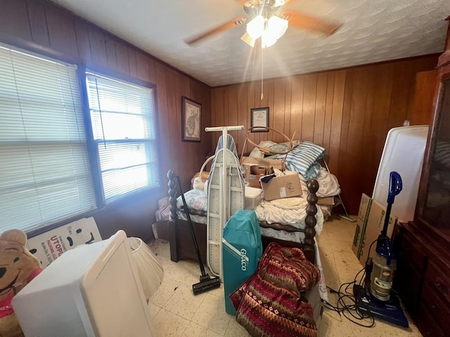 bedroom with ceiling fan and wooden walls