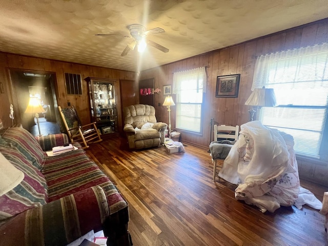 living room featuring ceiling fan, wood walls, and hardwood / wood-style flooring