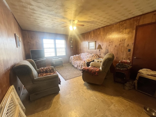 living area with a textured ceiling, ceiling fan, and wood walls