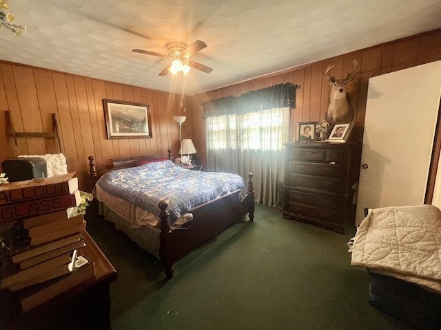 carpeted bedroom with ceiling fan, wooden walls, and a textured ceiling