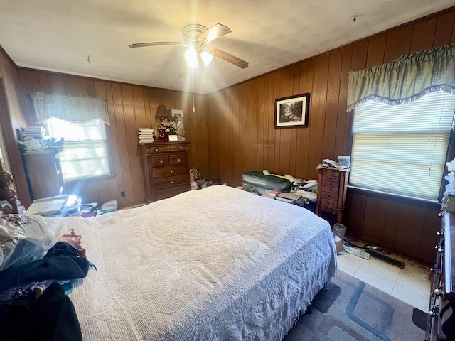 bedroom featuring ceiling fan and wood walls