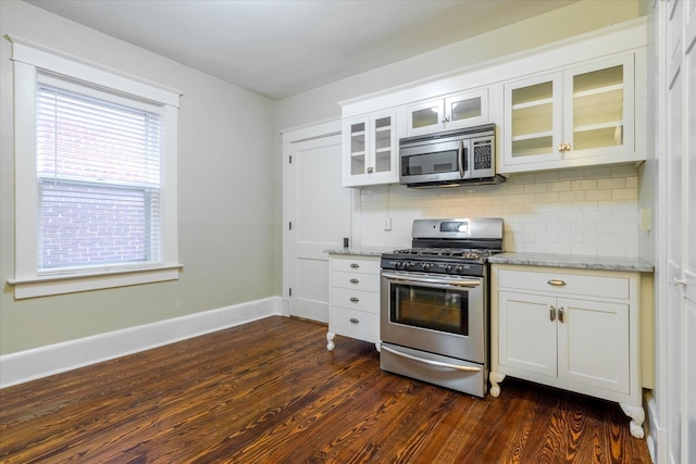 kitchen featuring dark wood-type flooring, white cabinets, decorative backsplash, appliances with stainless steel finishes, and light stone counters