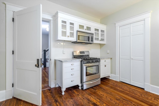 kitchen featuring decorative backsplash, white cabinetry, light stone counters, and appliances with stainless steel finishes