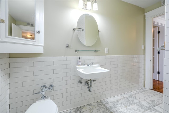 bathroom featuring toilet, tile walls, and sink