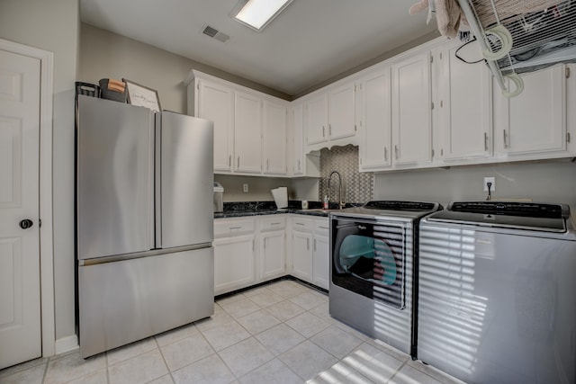 kitchen with white cabinetry, sink, stainless steel fridge, light tile patterned floors, and washer and dryer