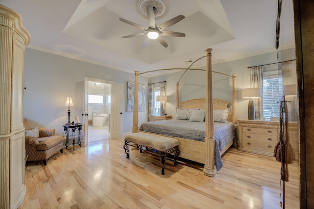 bedroom with ensuite bath, ornamental molding, a raised ceiling, ceiling fan, and light hardwood / wood-style flooring