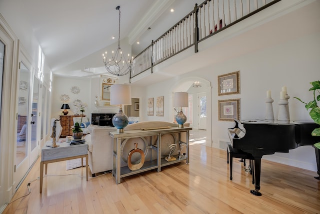 living room with a high ceiling, light wood-type flooring, and an inviting chandelier