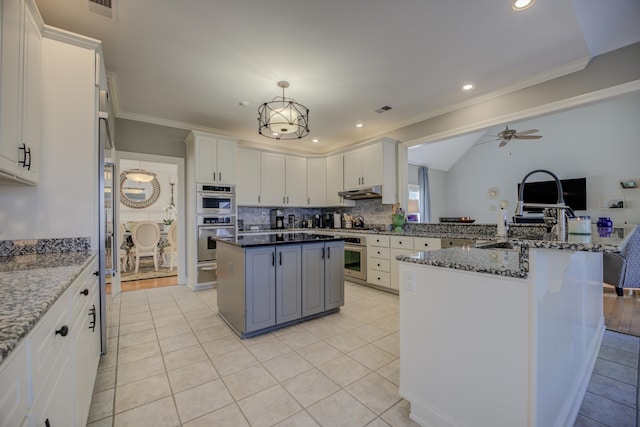 kitchen featuring a center island, white cabinetry, double oven, and dark stone counters