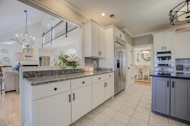 kitchen featuring white cabinets, hanging light fixtures, dark stone countertops, tasteful backsplash, and a notable chandelier