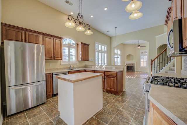 kitchen with decorative light fixtures, a center island, stainless steel appliances, and a high ceiling