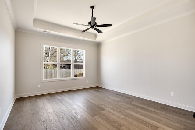 spare room featuring hardwood / wood-style flooring, a raised ceiling, ceiling fan, and ornamental molding