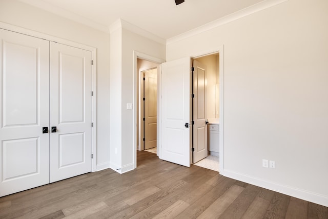 unfurnished bedroom with connected bathroom, light hardwood / wood-style flooring, a closet, and crown molding