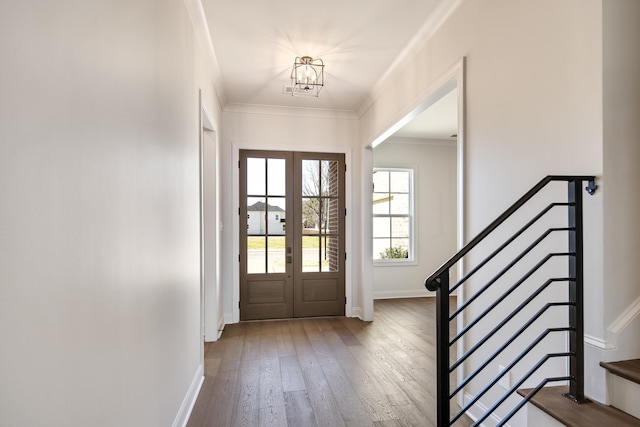 entrance foyer featuring a notable chandelier, wood-type flooring, crown molding, and french doors