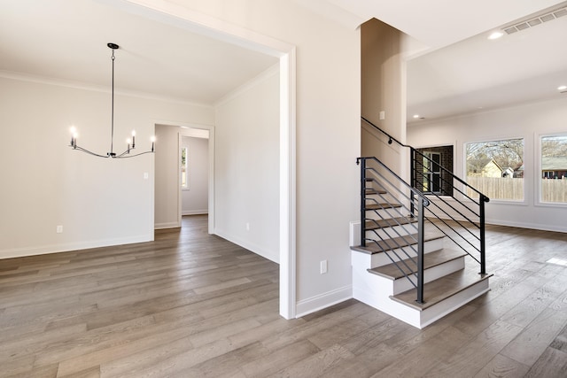 stairway with hardwood / wood-style flooring, crown molding, and an inviting chandelier