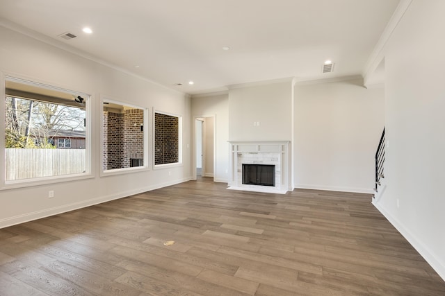 unfurnished living room with a tiled fireplace, crown molding, and wood-type flooring