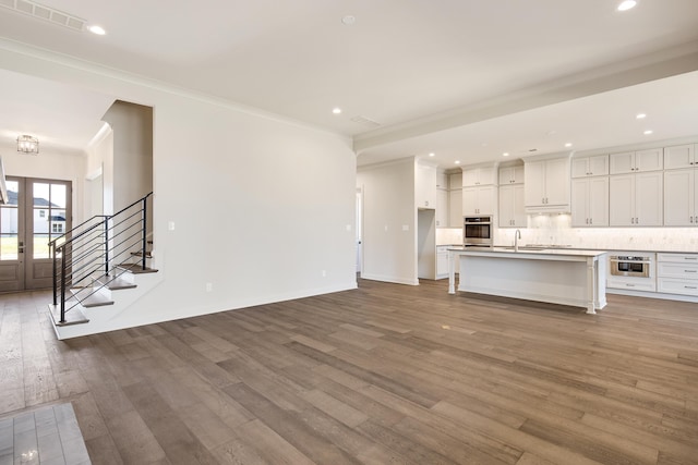 unfurnished living room with hardwood / wood-style flooring, crown molding, and sink