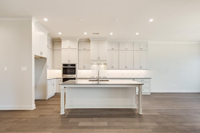 kitchen with white cabinetry, an island with sink, stainless steel double oven, and dark hardwood / wood-style floors